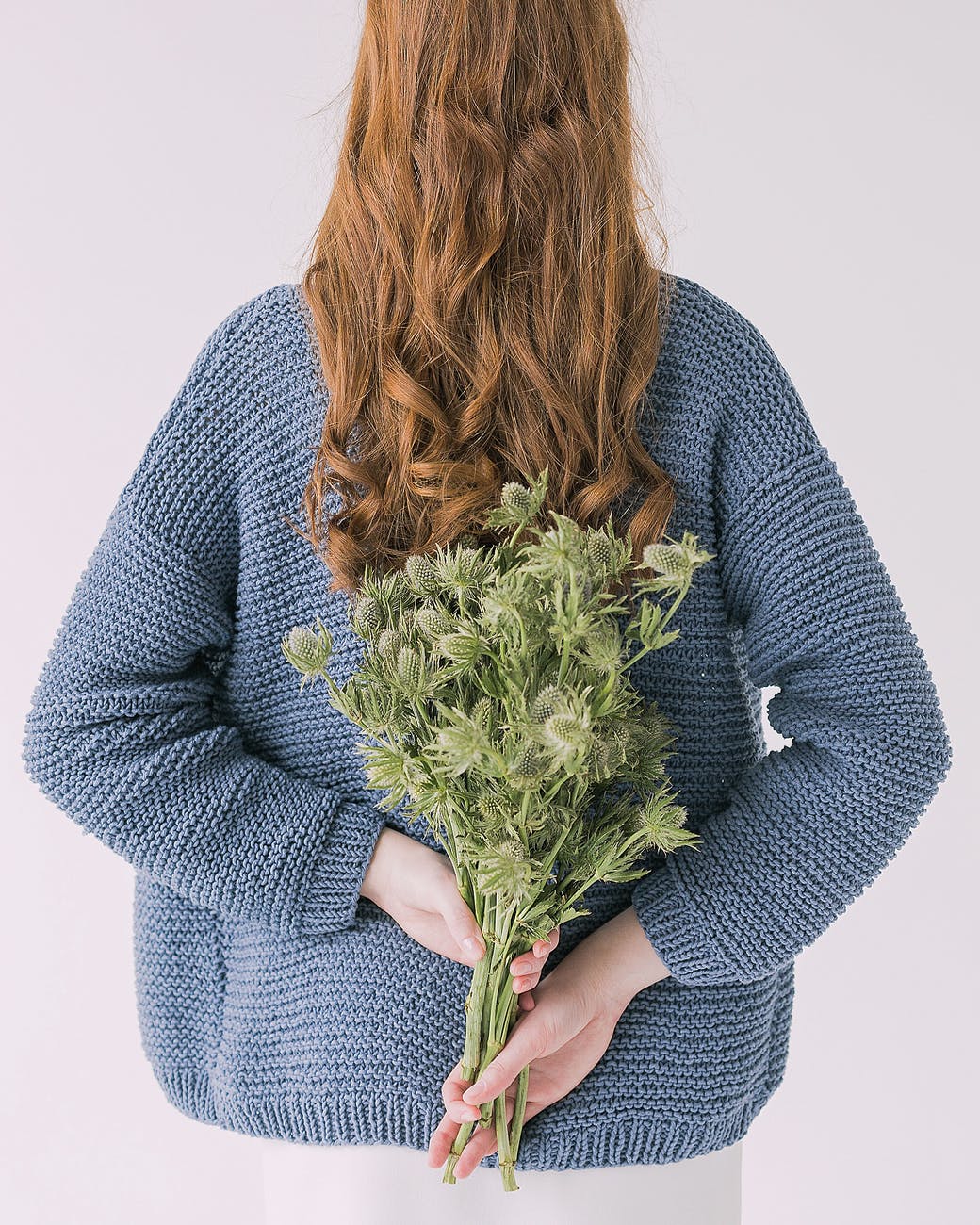 woman in gray sweater holding green leaf plants